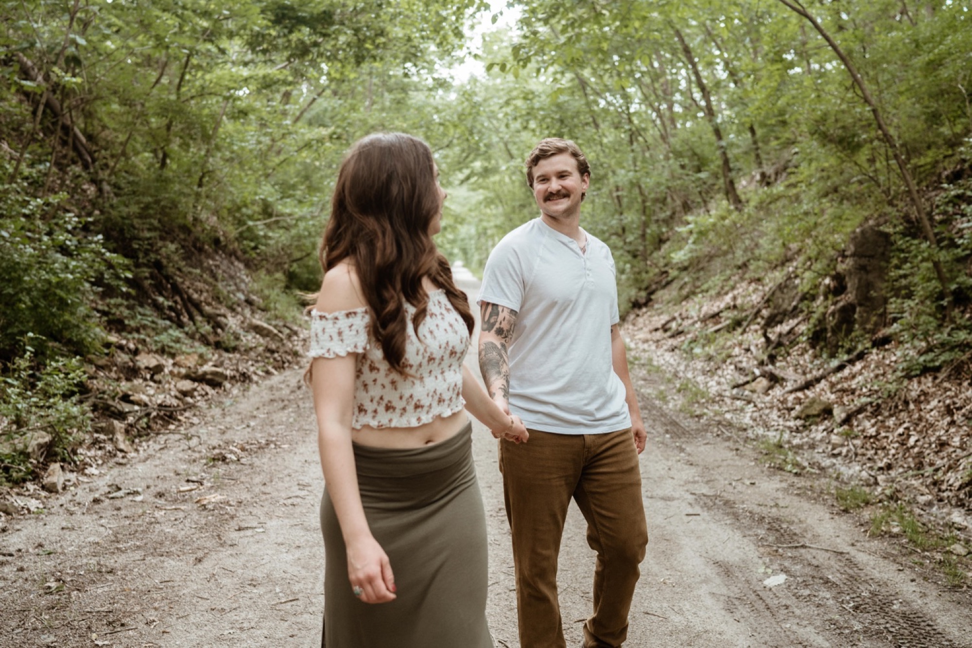 couple walking hand in hand on a trail during winterset park engagement session