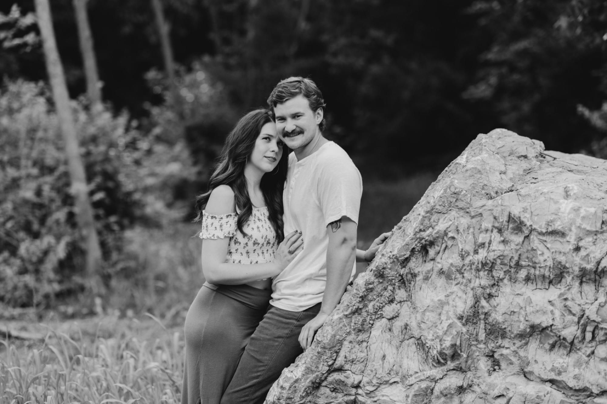 couple in b&w cuddling against rock in winterset engagement session