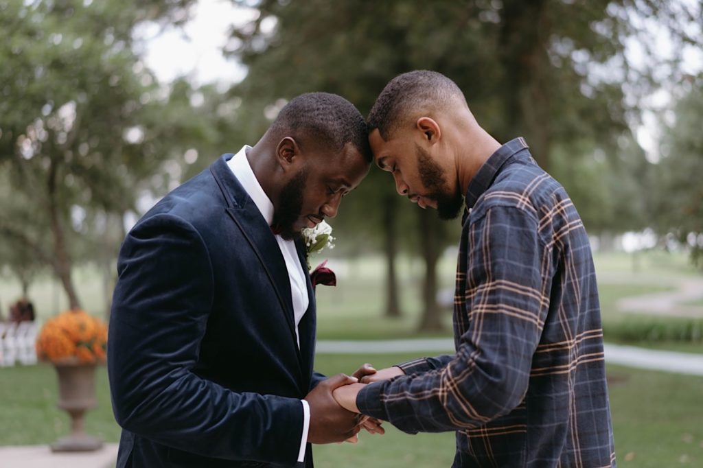 groom and his brother pray together before groom's intimate backyard wedding