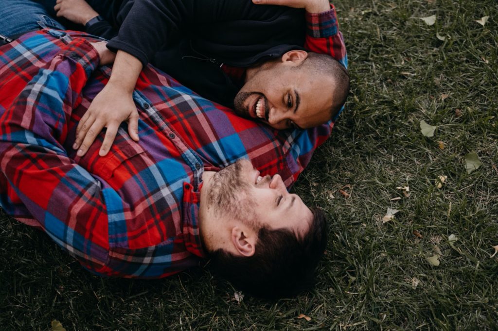 couple cuddles together on the ground at loose park engagement