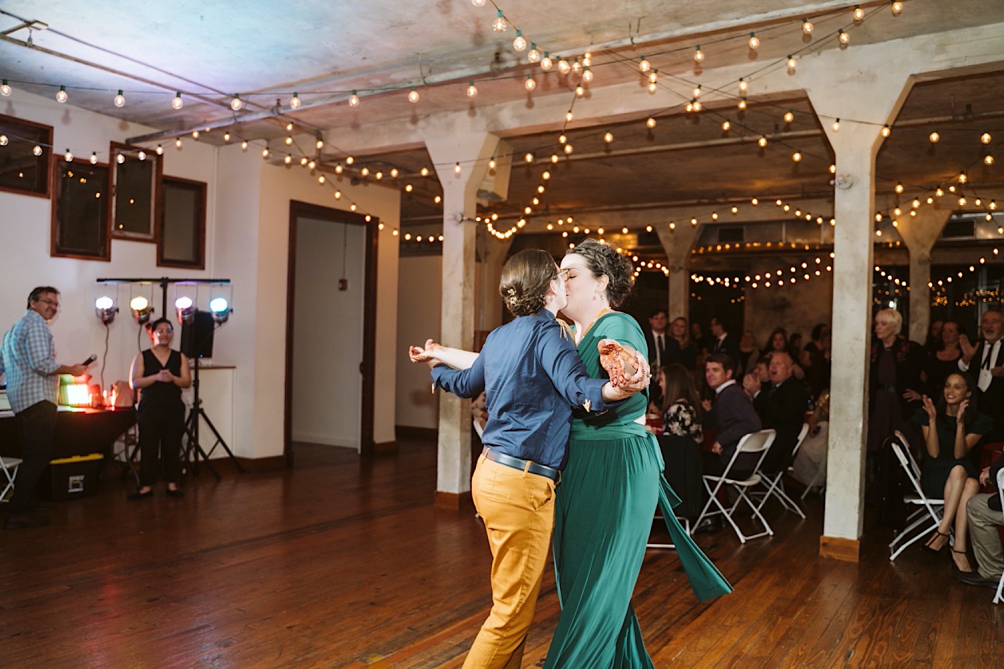 LGBTQ+ couple kisses on dance floor of bride and bauer sustainable wedding