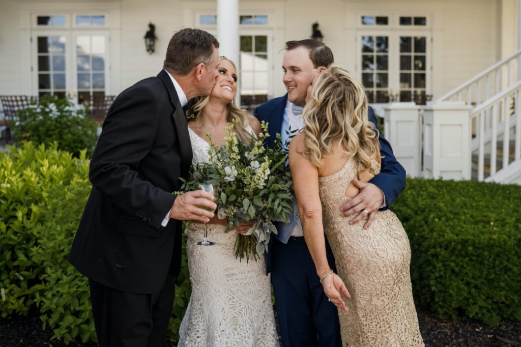 parents kissing bride and group at kc national golf club