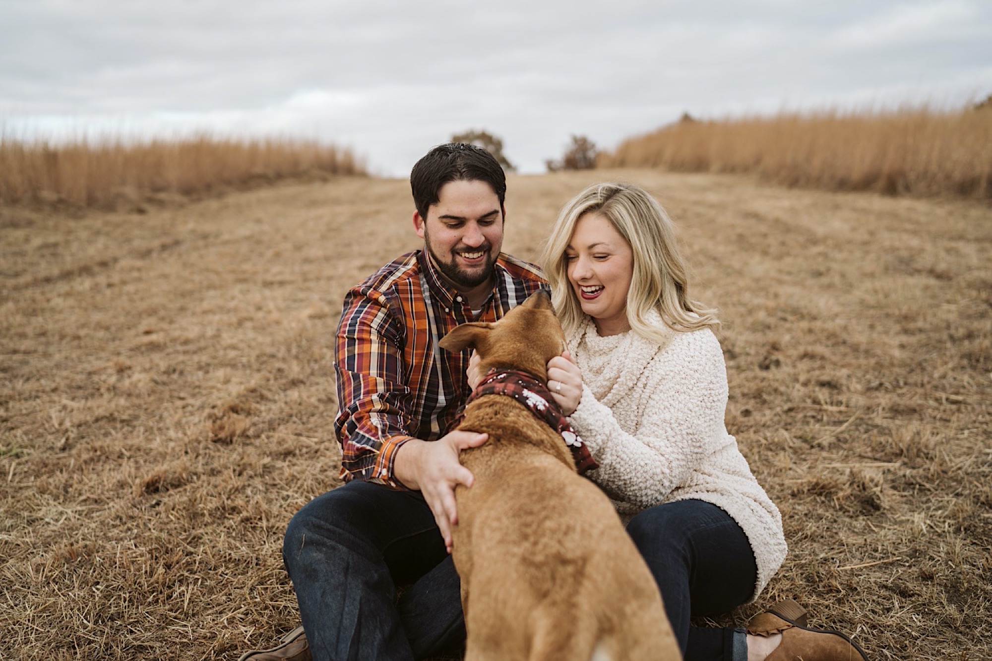 couple cuddles with dog during shawnee mission park engagement
