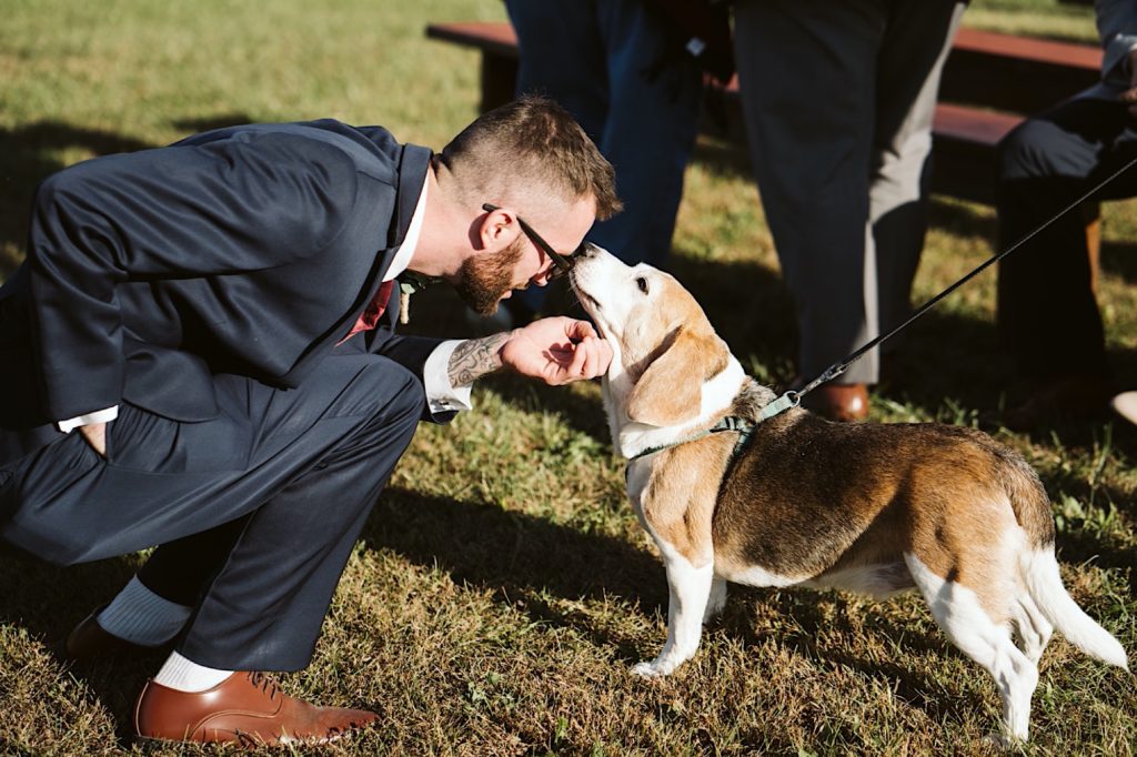 groomsman kisses dog at sweet clover farms wedding