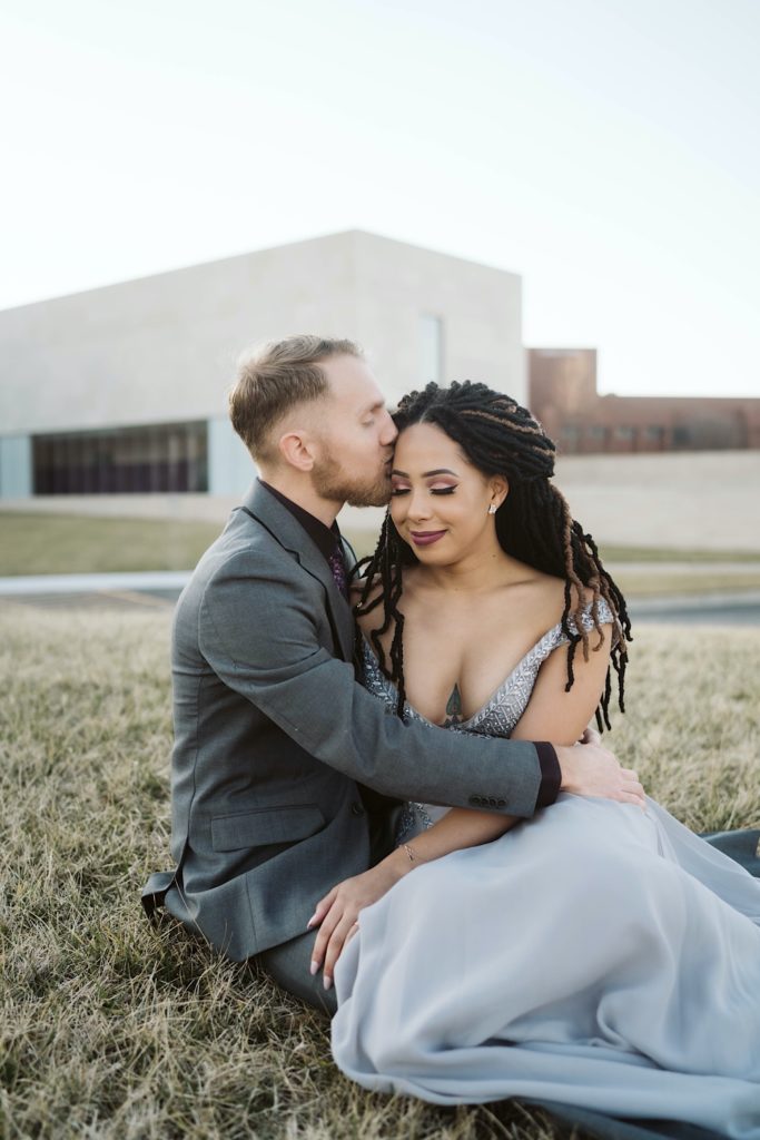 Couple cuddles in front of nerman museum during elegant engagement session