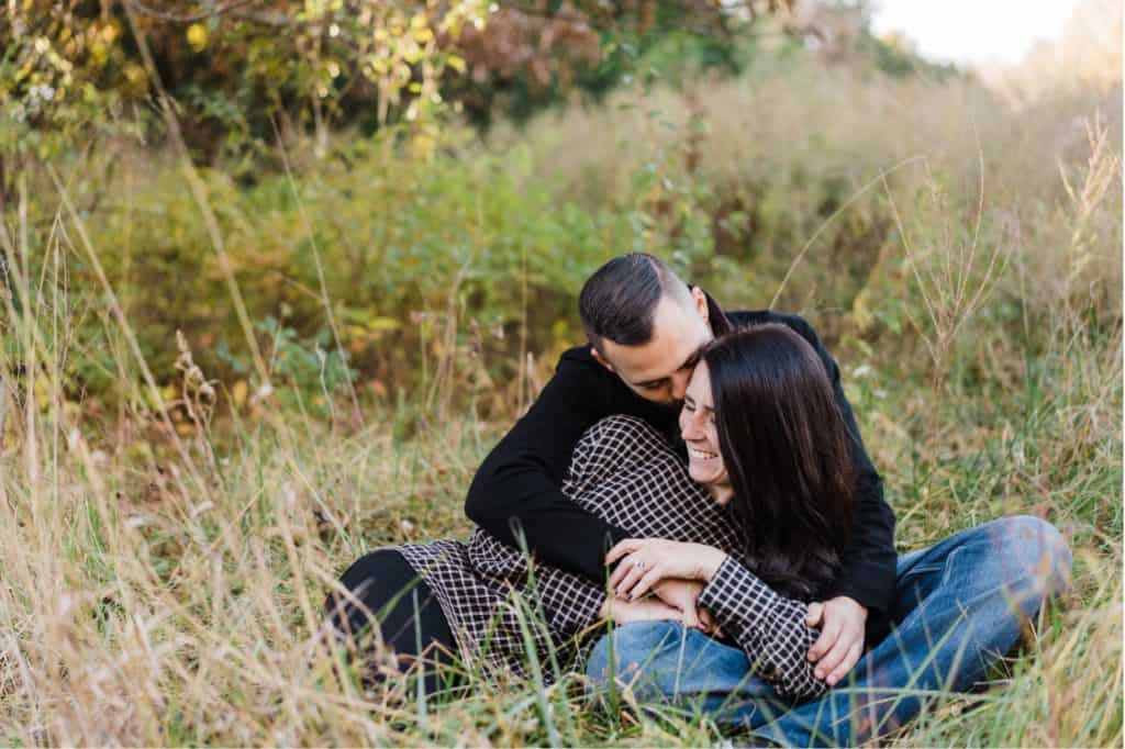 couple cuddles in the grass during their hodge park engagement session