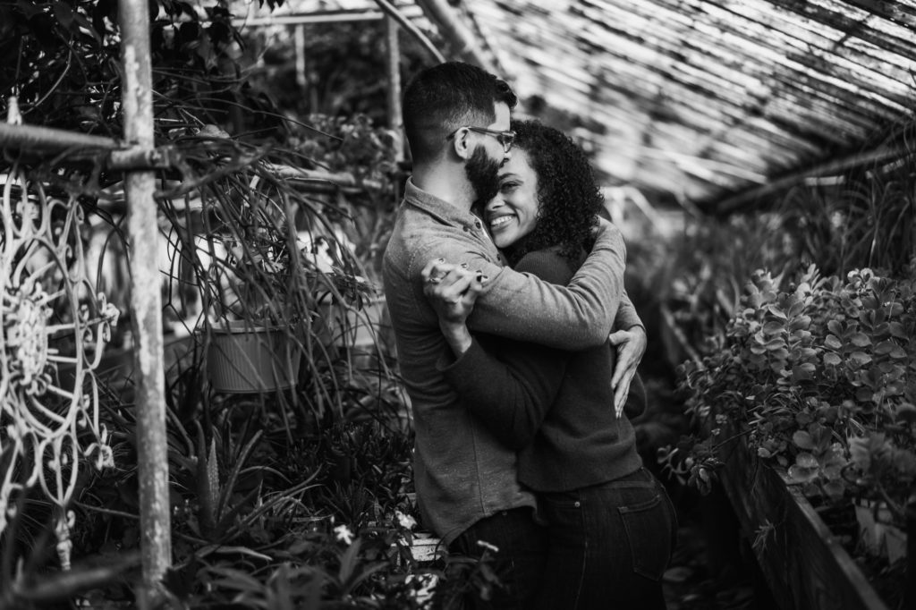 black and white photo of couple smiling during john's greenhouse engagement