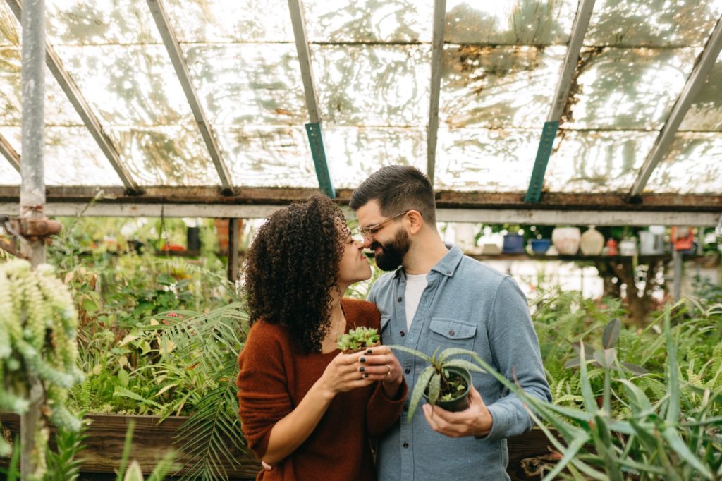 Clients hold favorite plants at John's Greenhouse Engagement Session