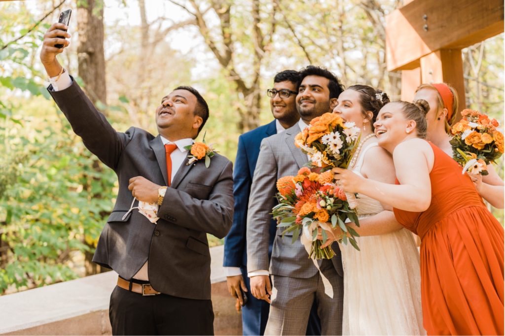 bride and groom take selfie with wedding party during overland park arboretum wedding