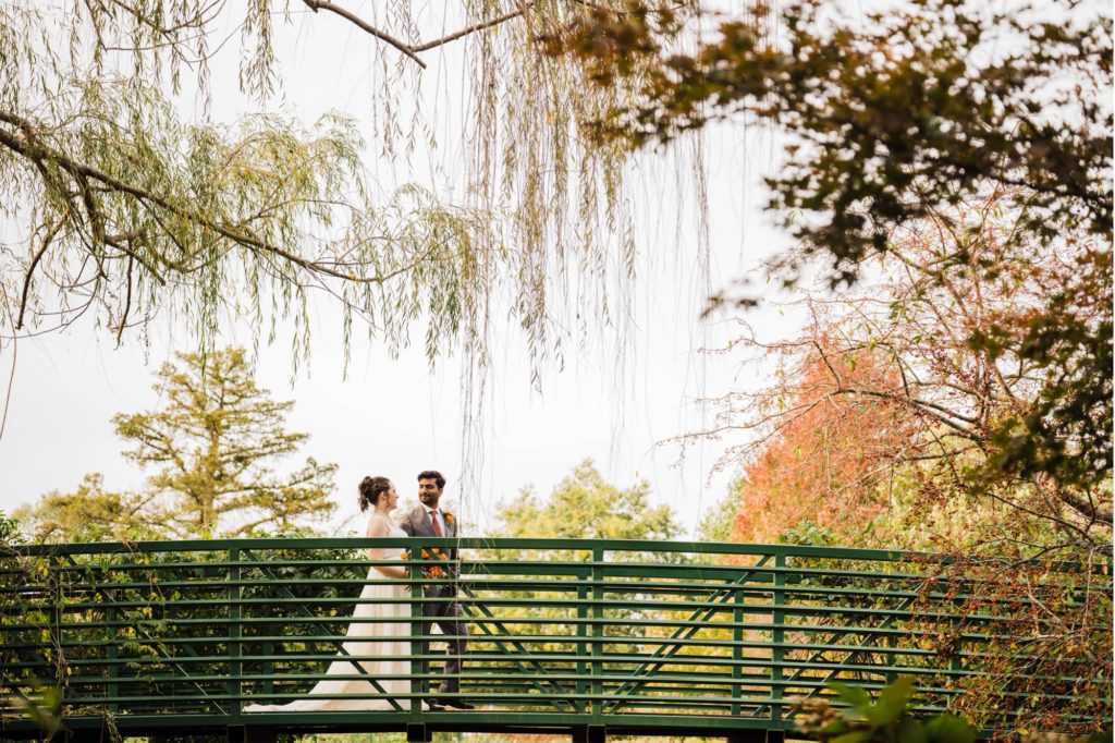 Newlywed couple walks on Monet Bridge at Overland Park Arboretum Wedding