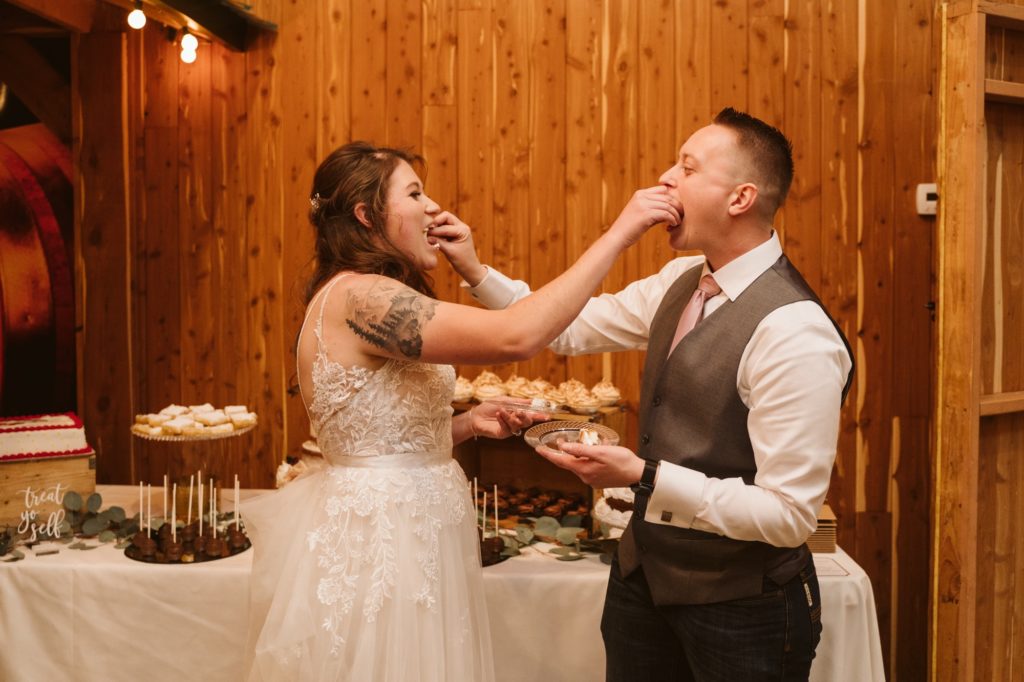 LGBTQ+ couple feeds each other cake at Little Piney Lodge Wedding