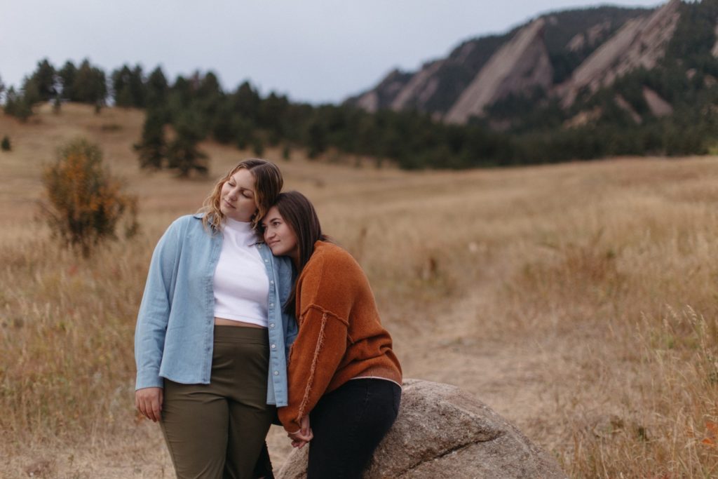 One woman snuggles against her partner's body at Chautauqua Park Engagement Session